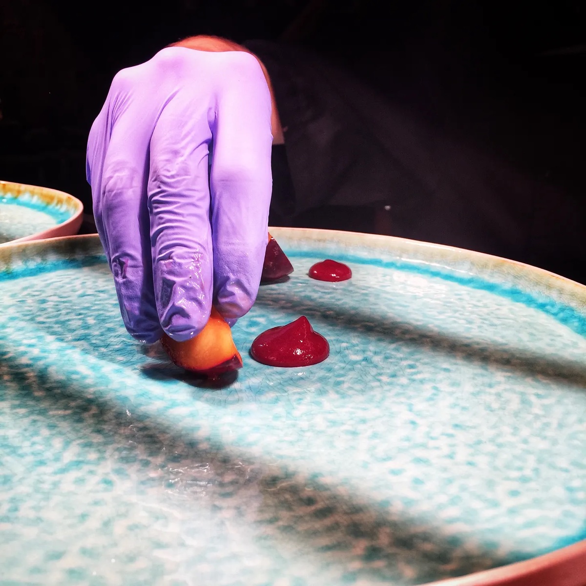 A gloved hand placing food on a restaurant plate